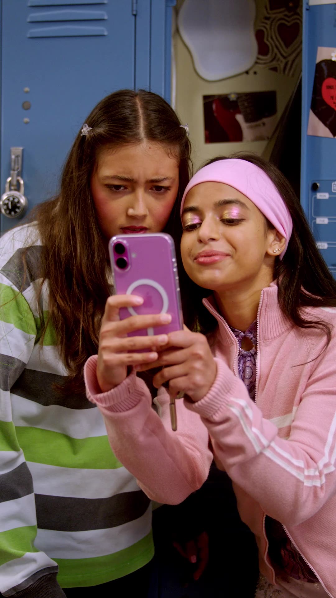 Strings Attached — two friends looking at a phone together at their lockers
