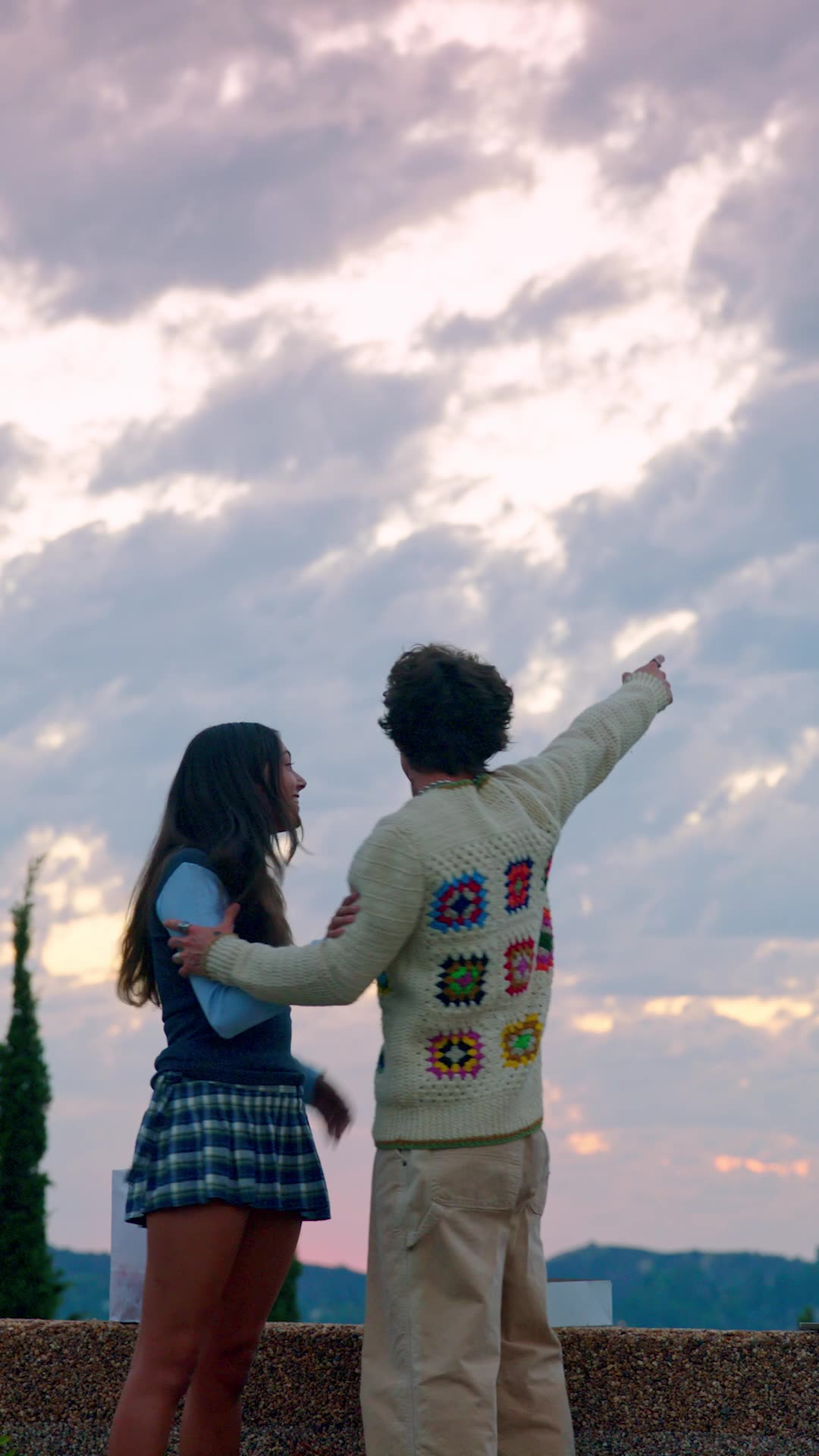 Strings Attached — a couple watching the sunset, one pointing at the sky